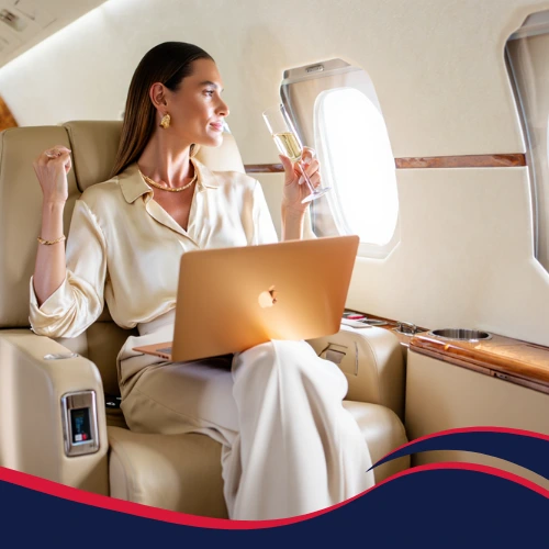 Fashion model enjoying champagne and working on laptop in private jet cabin — Frenchway experience