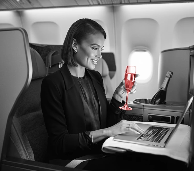 Businesswoman with laptop and champagne in business class — VIP corporate travel experience