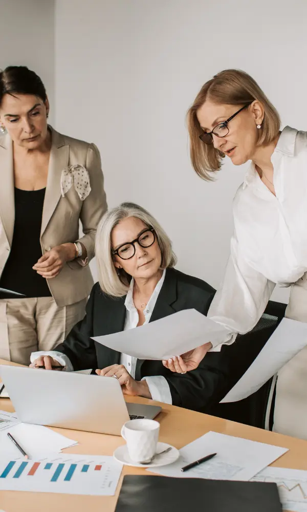 Finance team reviewing corporate travel expense reports and budget analytics on laptop in an office meeting