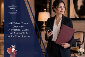 Editorial cover image for a VIP talent travel checklist article, showing a professional travel coordinator in a luxury hotel lobby holding a smartphone and red folder, with luggage and planning materials in the background.