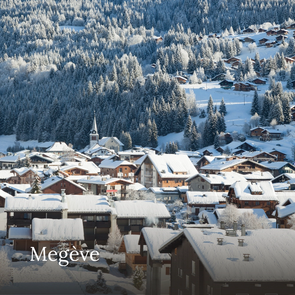 Snow-covered Alpine village with traditional wooden chalets, a church and forested mountains in Megève, France