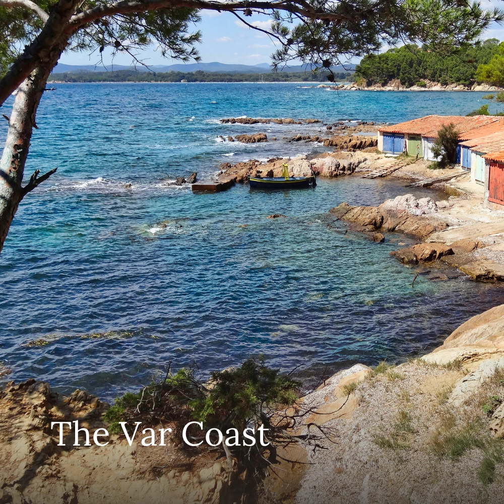 Rocky Mediterranean cove with turquoise water, pine trees and traditional coastal buildings on the Var coast, France